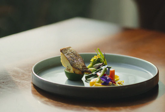 A sleek, modern seafood dish plated with fresh fish and garnishes in a minimalist blue and white setting.
