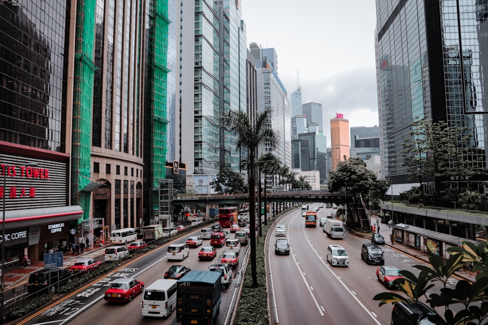 cars on road between high rise buildings during daytime