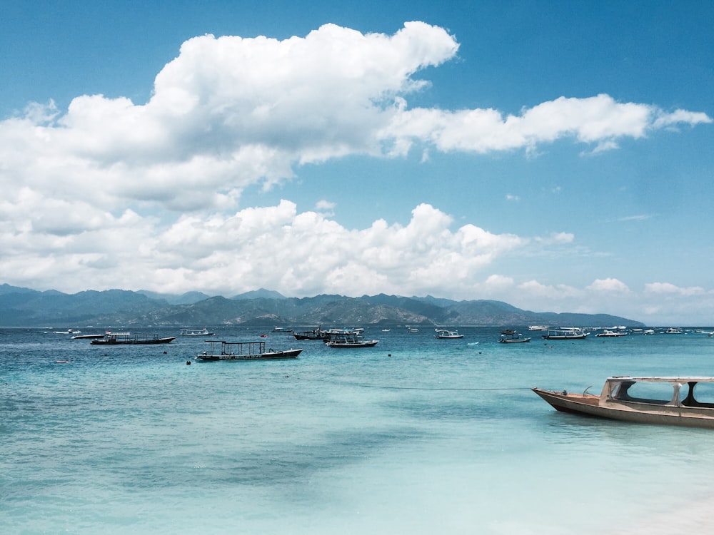 white and brown boat on sea under white clouds and blue sky during daytime