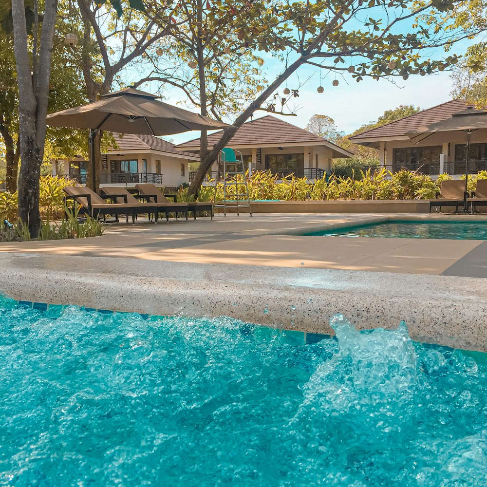 Casa de concreto marrom e branco perto de árvores verdes e piscina durante o dia