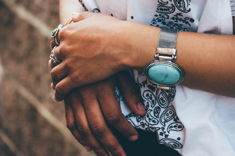 person wearing silver link bracelet round analog watch