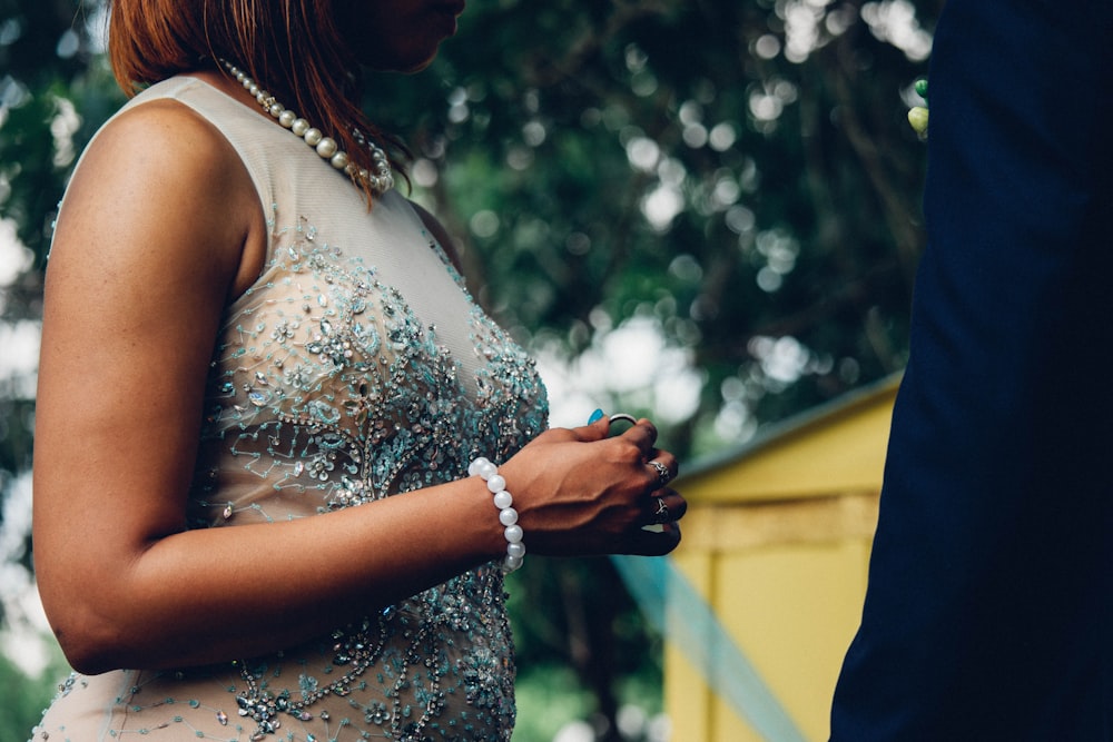 woman in white sleeveless dress holding hands with man in black suit