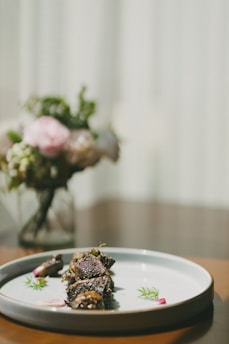 A close-up shot of a vibrant, freshly plated signature dish with delicate garnishes on a minimalist white plate.