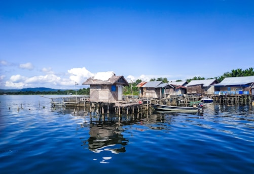 white and brown wooden houses on body of water under blue sky during daytime