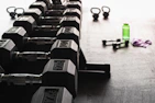 Fitness equipment like dumbbells and water bottles presented on clean white background