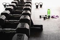 A set of colorful dumbbells and a water bottle arranged neatly on a gym floor.