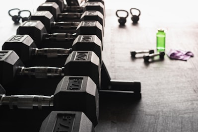 A set of durable dumbbells and kettlebells arranged neatly on a wooden floor.
