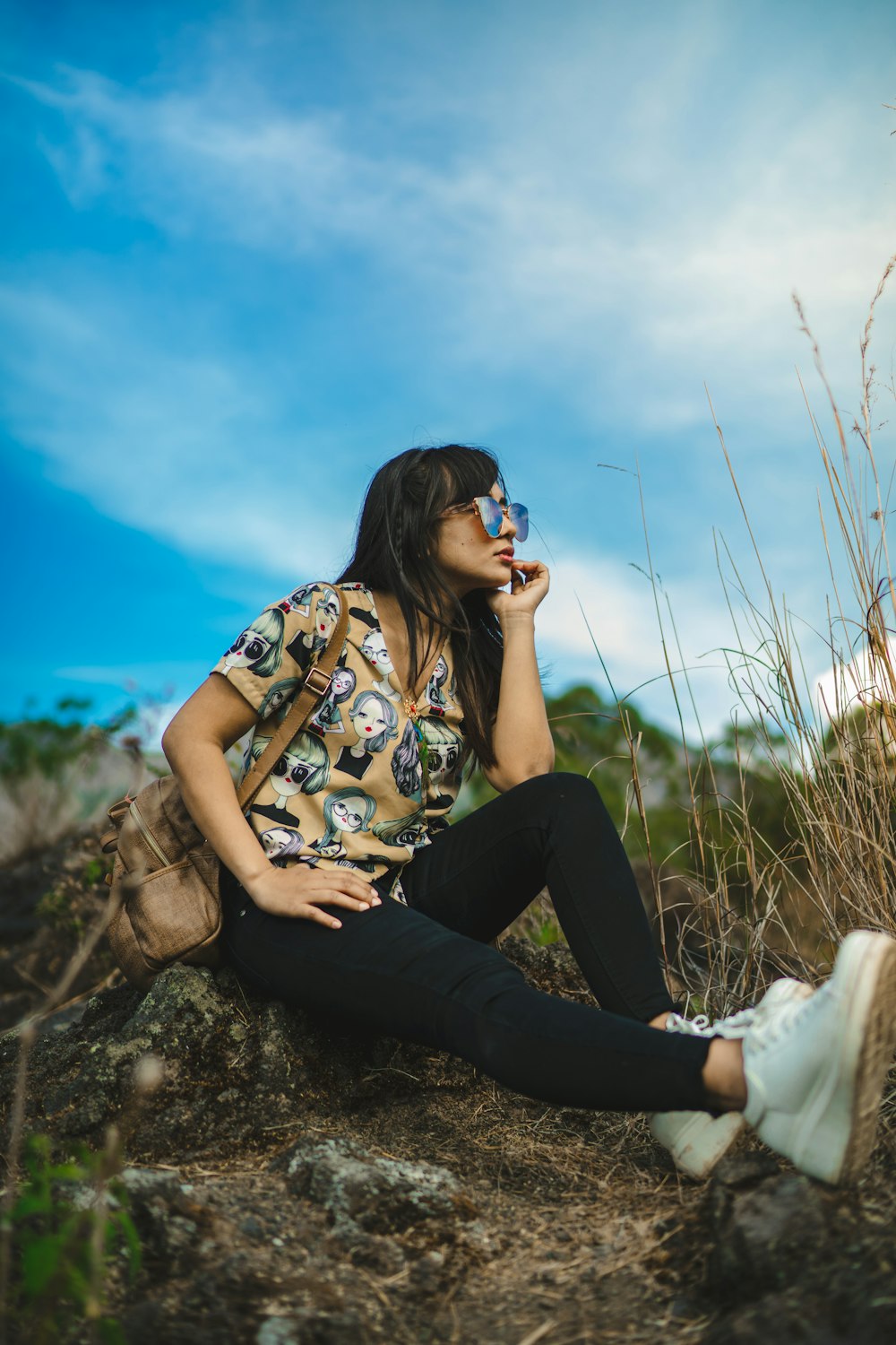 woman in black pants and white shirt sitting on brown rock during daytime