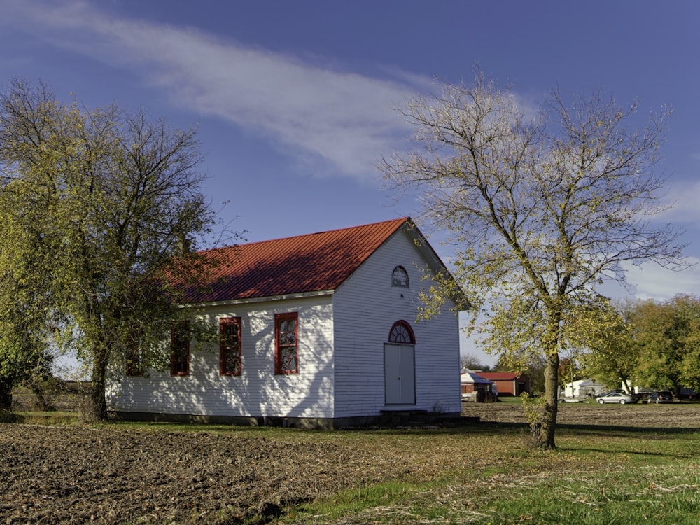 Weißes und rotes Haus in der Nähe von kahlen Bäumen unter blauem Himmel während des Tages