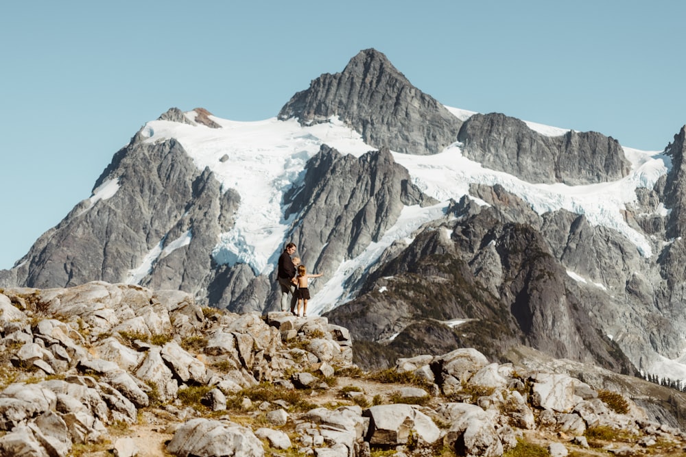 person in black jacket and brown pants standing on rocky mountain during daytime