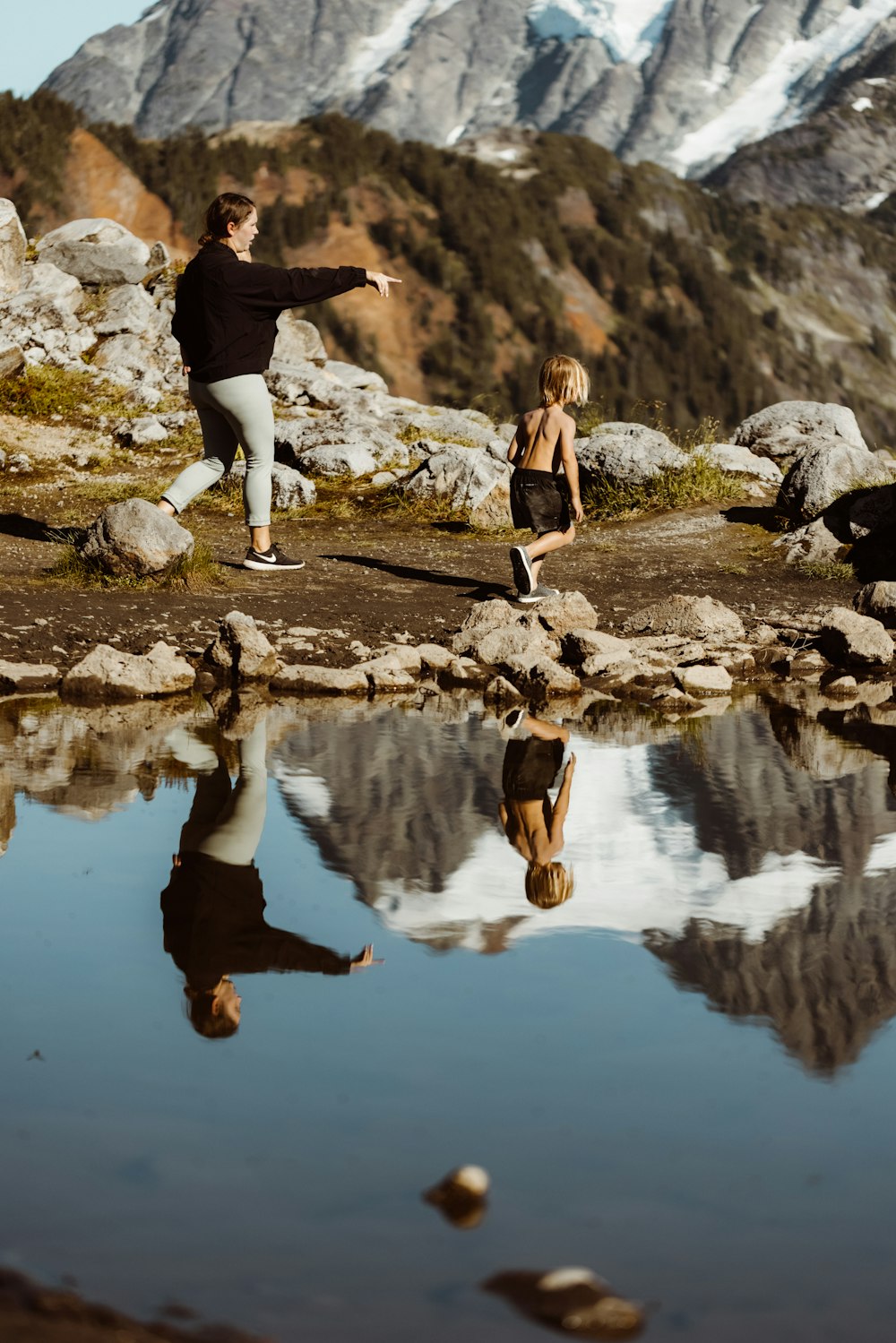 2 women in black shirt and black pants jumping on river during daytime