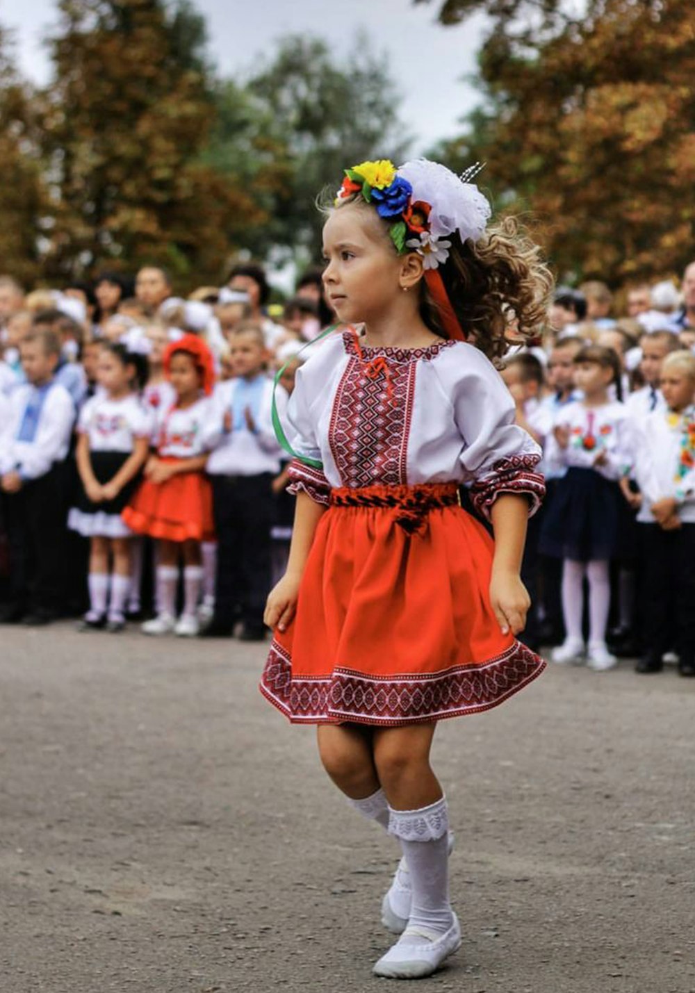 Mädchen in rot-weißem Kleid, das tagsüber auf grauem Betonboden steht