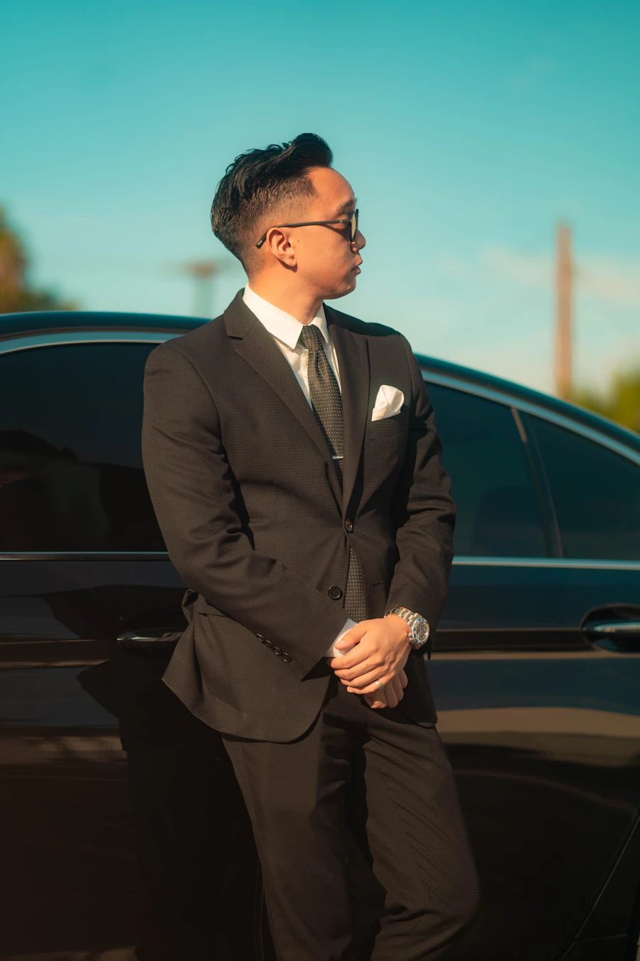 Chauffeur in a black suit beside a black car