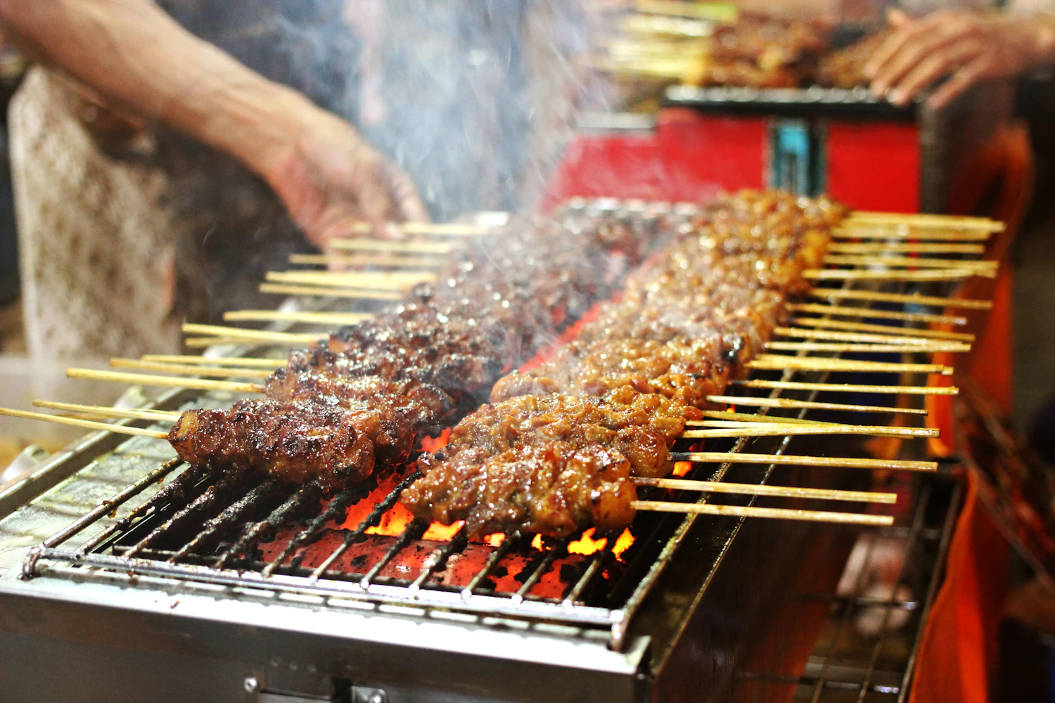 Satay skewers cooking over open charcoal at a stall