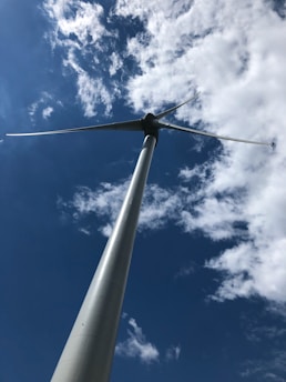 A vibrant wind turbine spinning gracefully against a bright blue sky dotted with fluffy clouds.