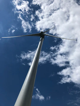 A wind turbine standing tall against a clear blue sky at sunset.