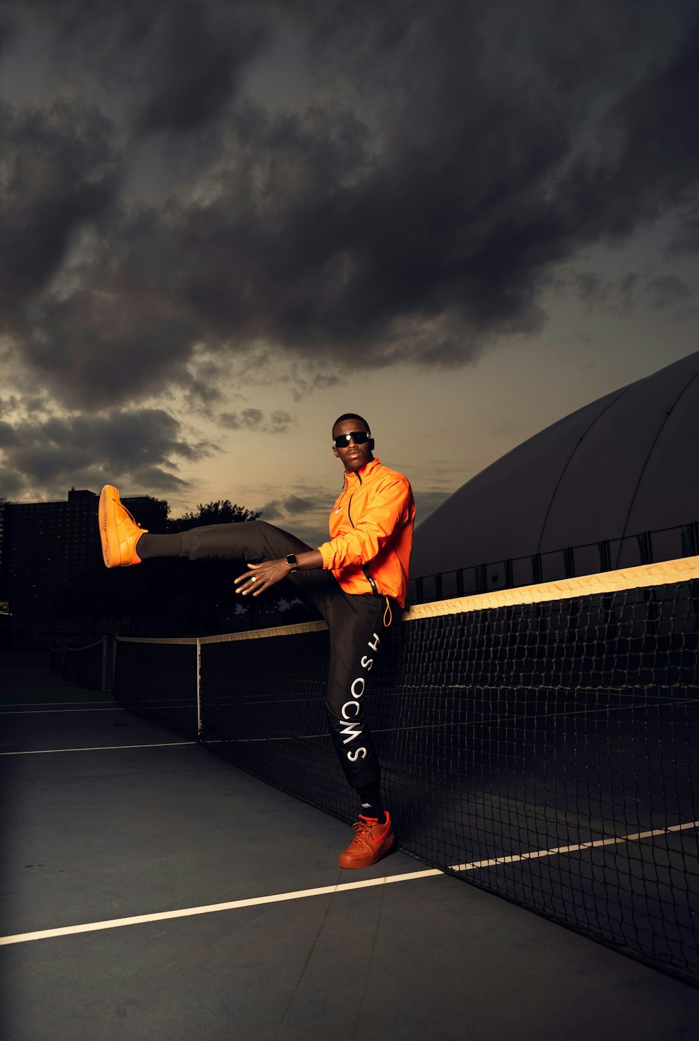 man in orange shirt and black pants standing on black bench