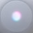 A circular, mesh-covered electronic device with a glowing light centered on the surface, displaying a gradient of colors including pink, blue, and white.