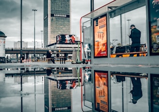 man in black jacket standing near glass window building during daytime