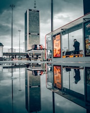 man in black jacket standing near glass window building during daytime