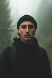 A cozy beanie resting on a moss-covered log in a misty Pacific Northwest forest.