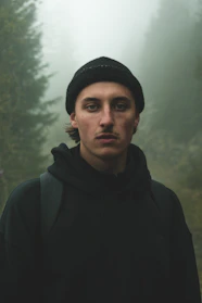 A cozy beanie resting on a moss-covered log in a misty Pacific Northwest forest.