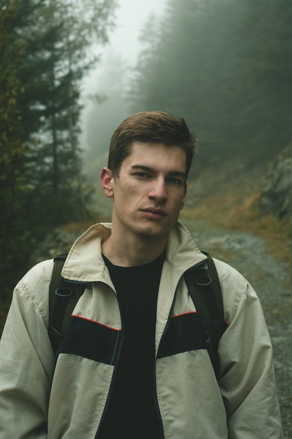 man in white jacket standing near green trees during daytime