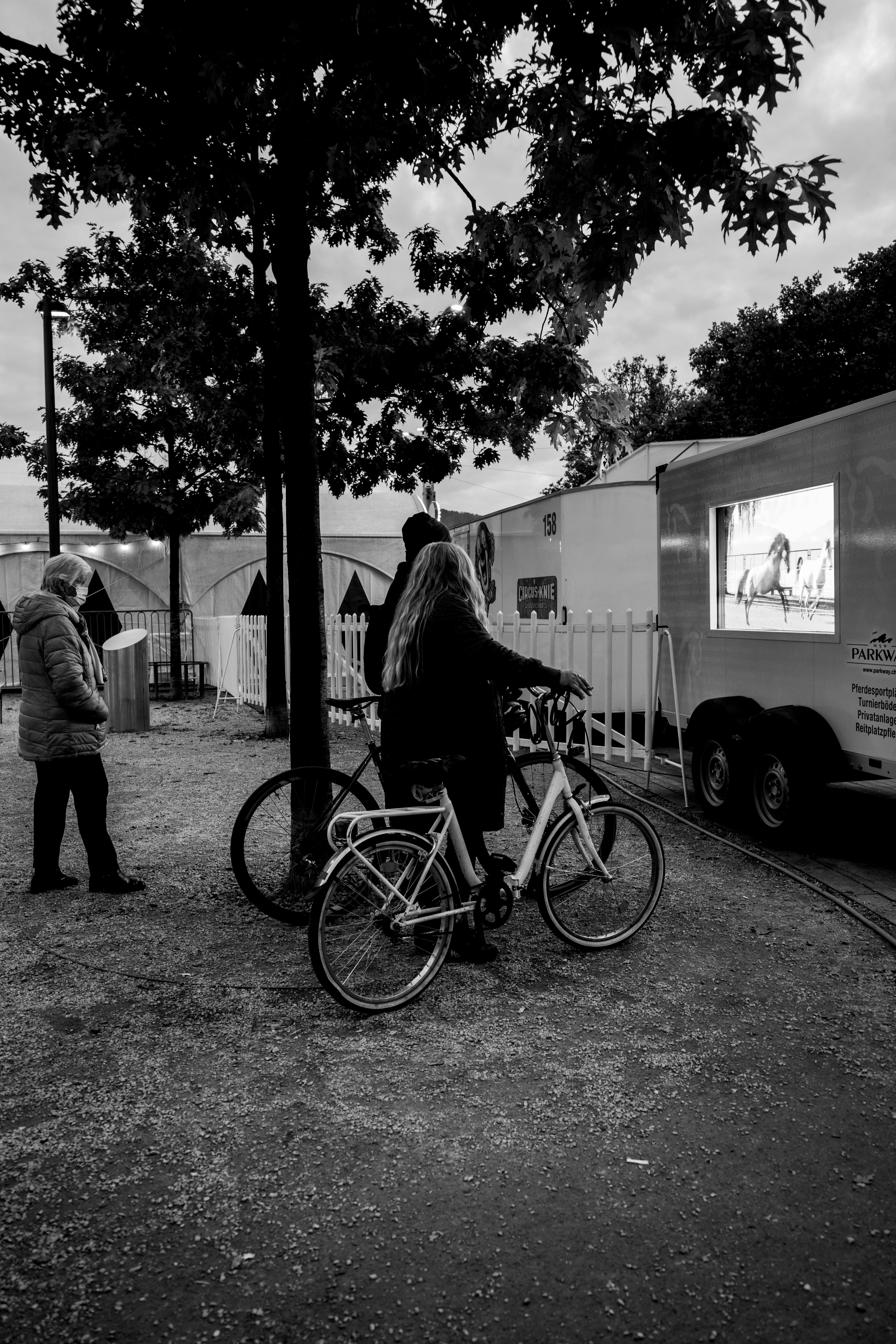 Grayscale photo of woman and man walking on sidewalk near bicycle ...