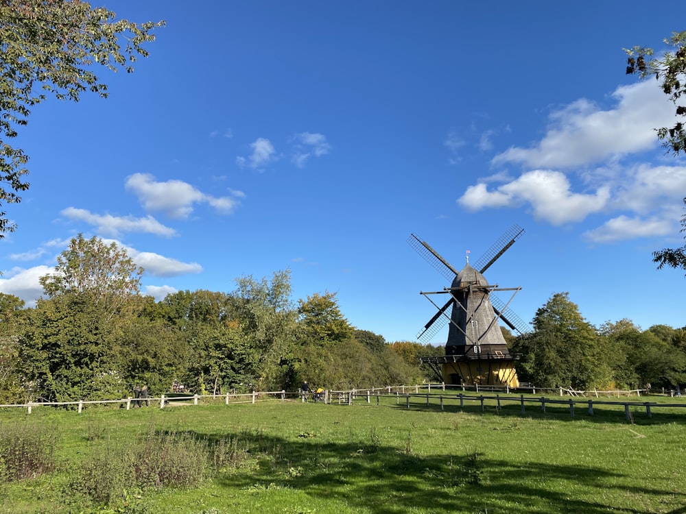 brown windmill on green grass field under blue sky during daytime