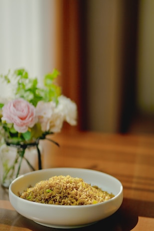 A bowl of cooked rice surrounded by fresh vegetables and herbs, symbolizing healthy eating.