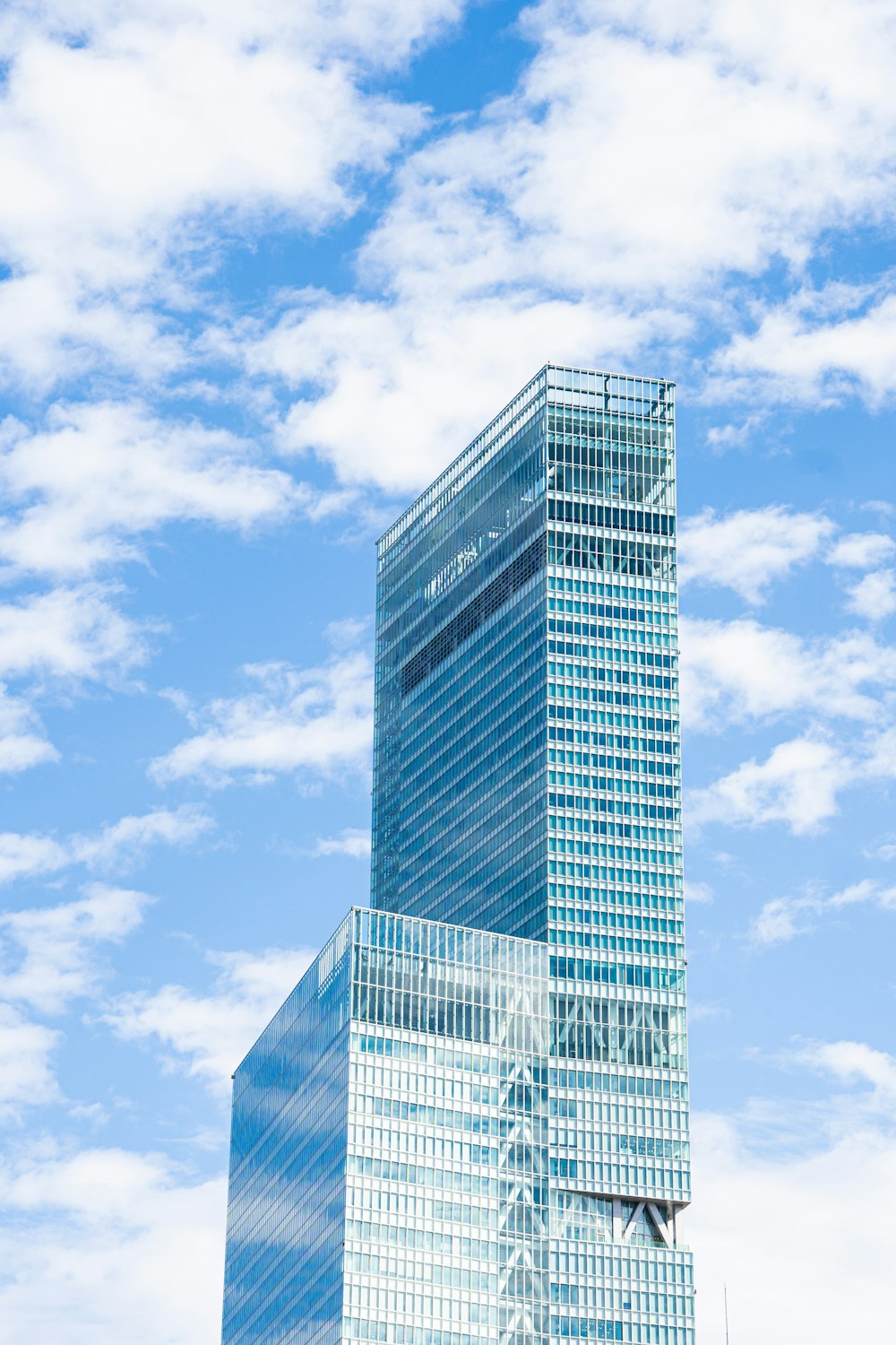 Edificio de gran altura con paredes de vidrio azul bajo el cielo azul durante el día