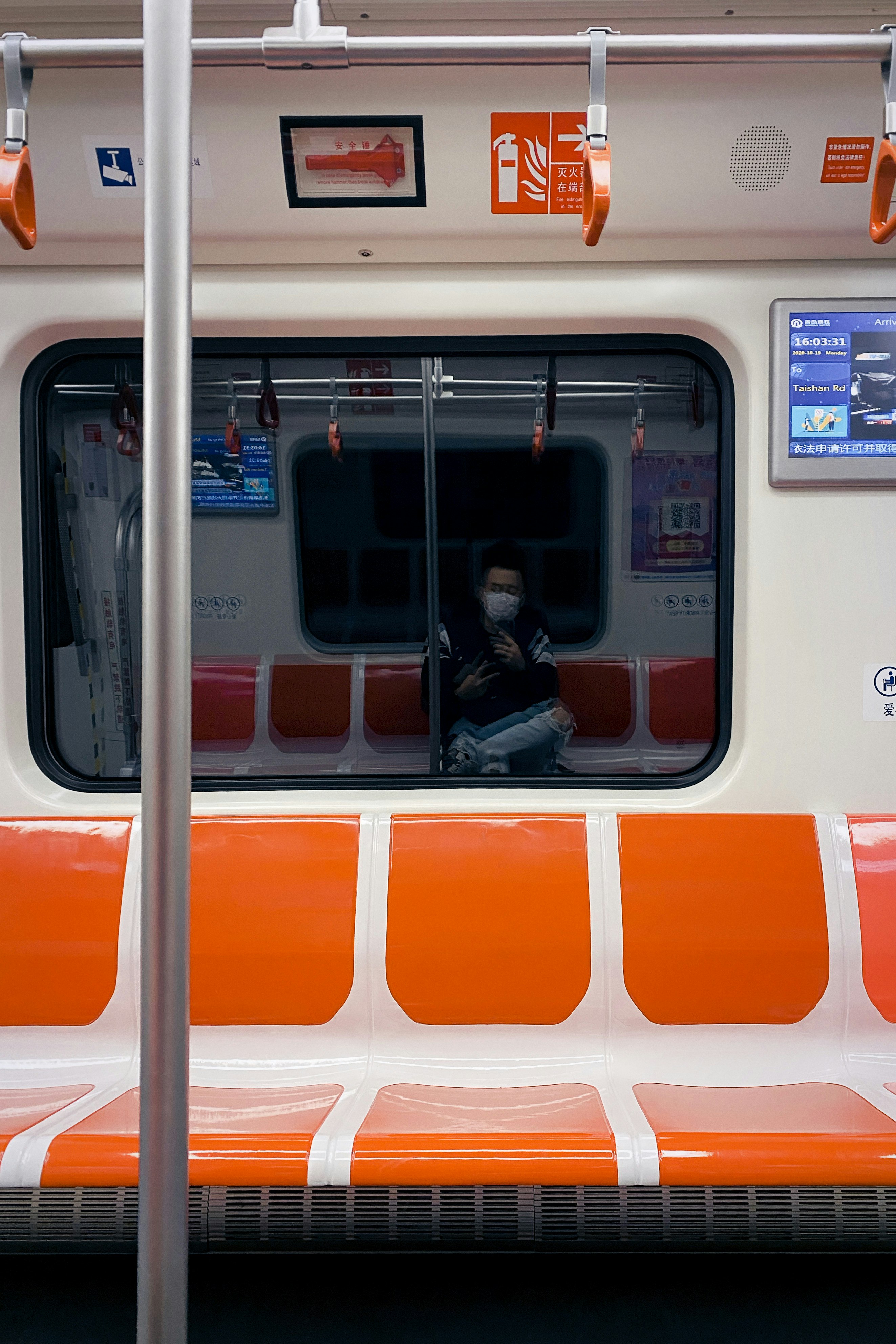 woman in black jacket and orange pants standing in front of white and orange train