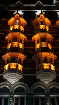 Nighttime façade lighting render highlighting architectural features with gold glow.