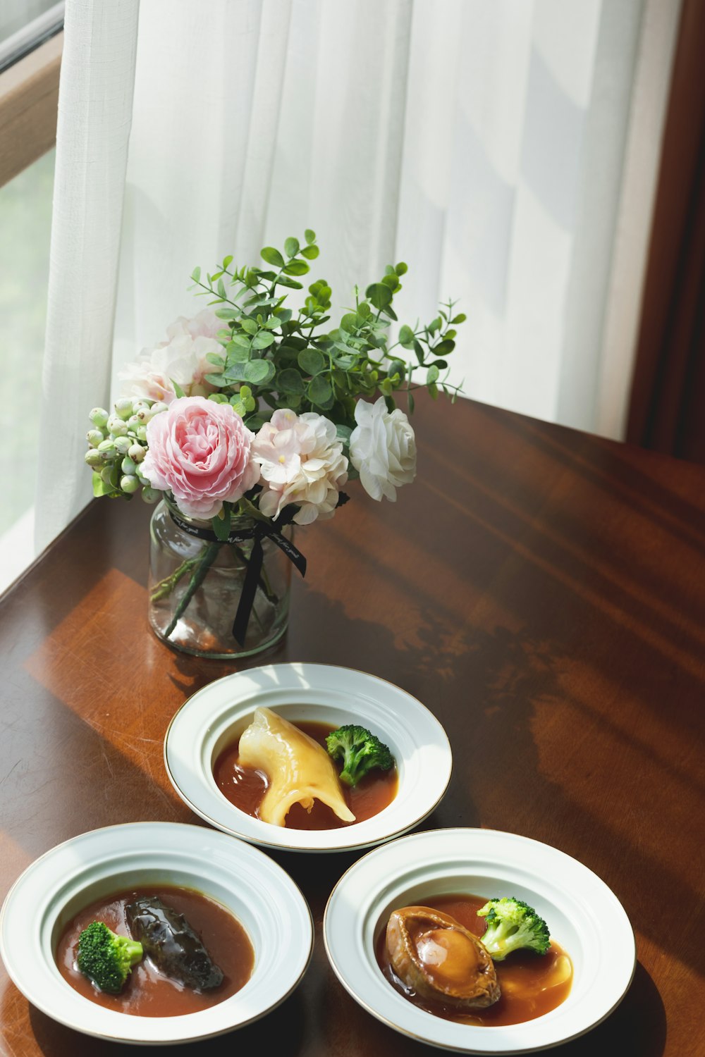 white and pink roses in clear glass vase on brown wooden table
