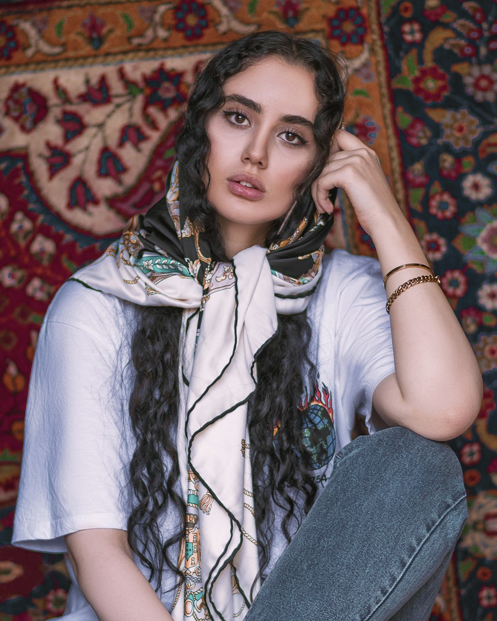 woman in white t-shirt and blue denim jeans sitting on red and brown floral sofa