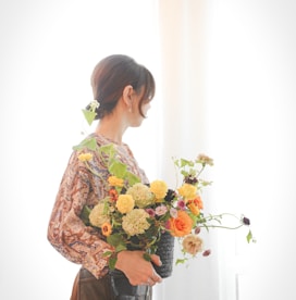 woman in green and yellow floral long sleeve shirt holding bouquet of flowers