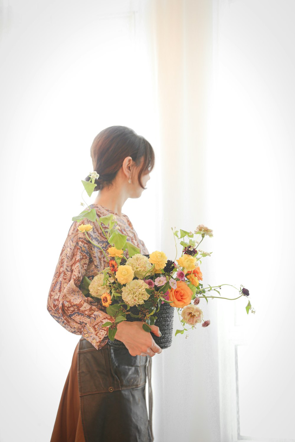 woman in green and yellow floral long sleeve shirt holding bouquet of flowers