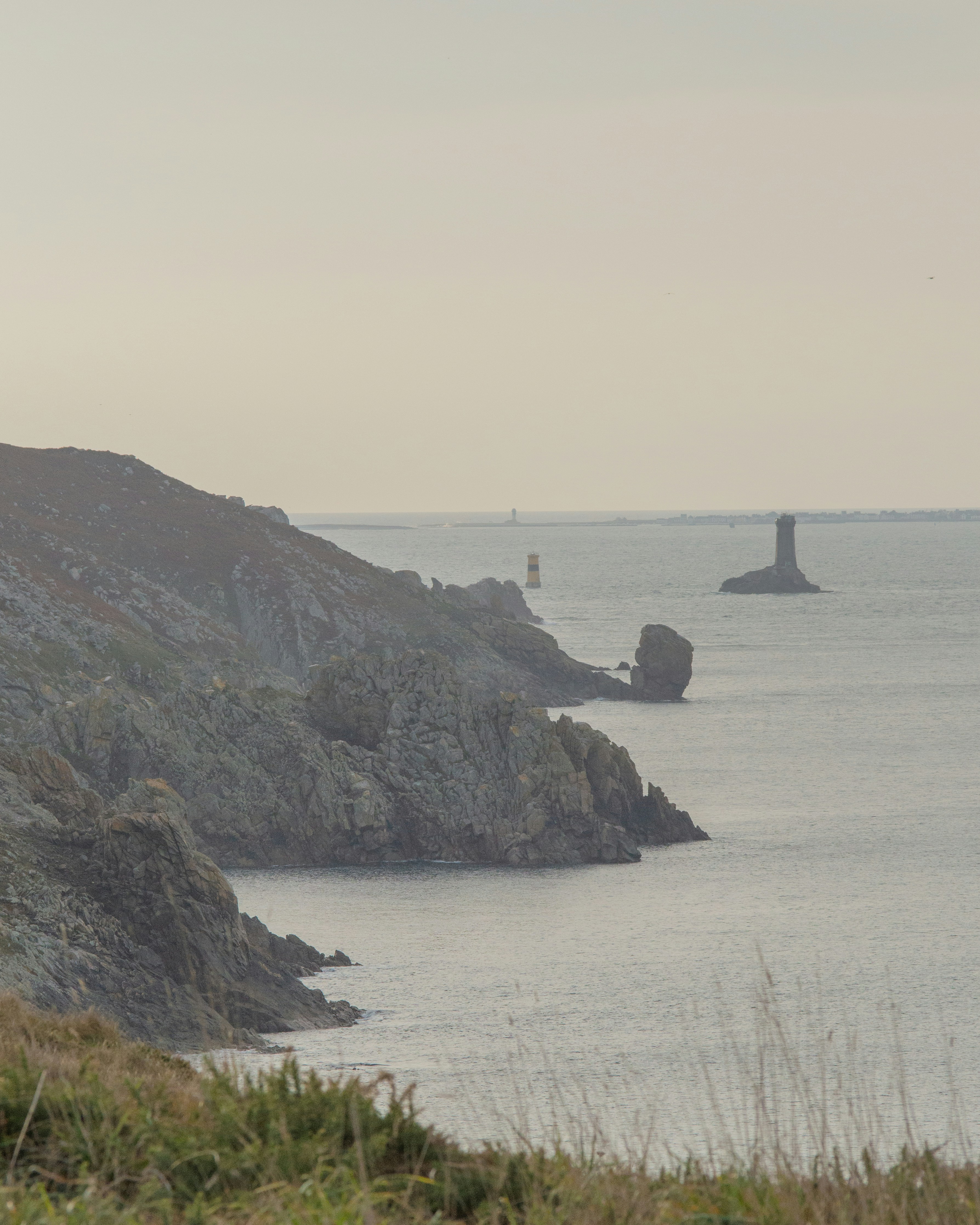 Misty rugged northern coastline with a boat making its way out to sea at sunrise