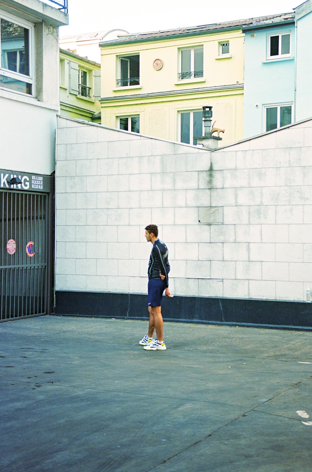 man in blue and white jacket and orange shorts walking on sidewalk during daytime