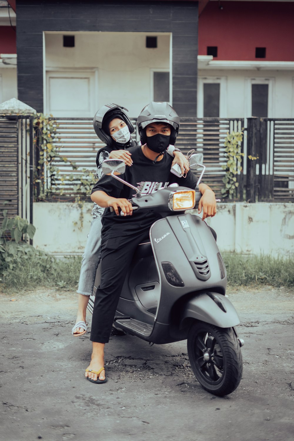 man in black t-shirt and gray shorts riding on gray motor scooter during daytime