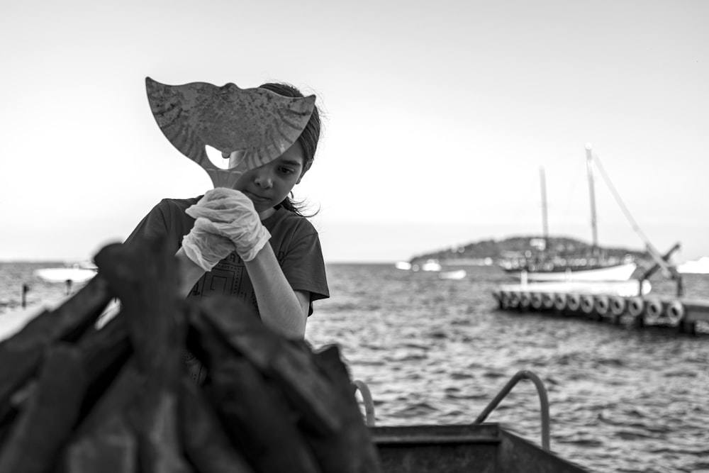 grayscale photo of woman in white shirt and hat sitting on boat