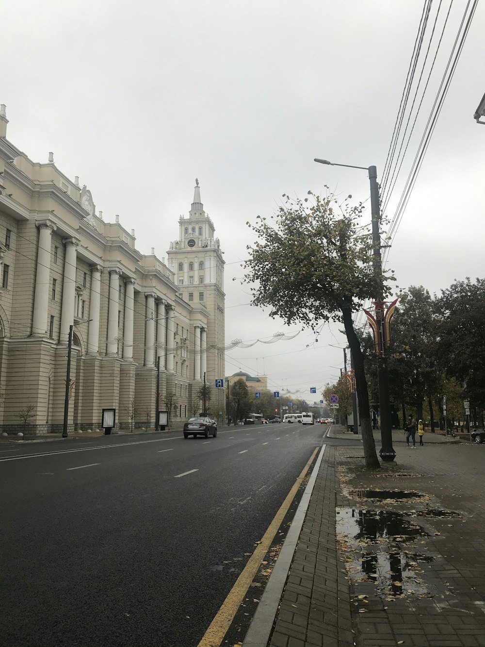 cars parked on side of the road near white concrete building during daytime