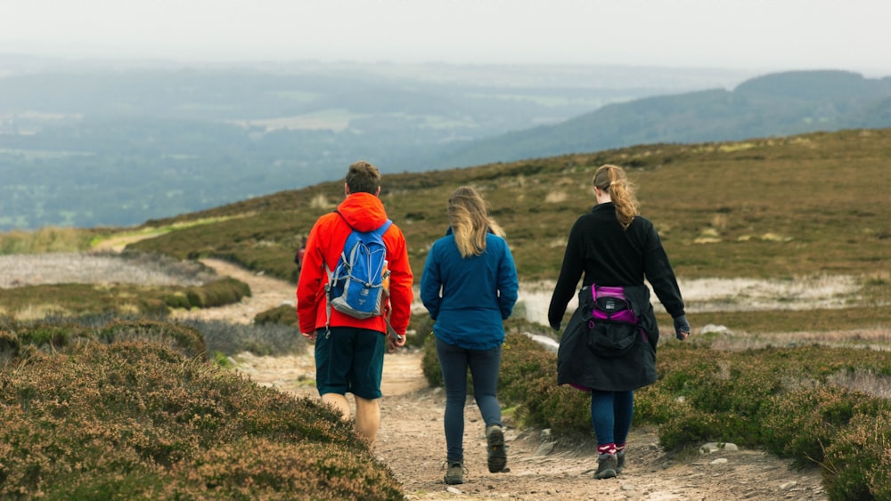 3 women walking on dirt road during daytime