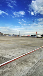 An airport runway with a cargo plane being loaded under a bright sky.
