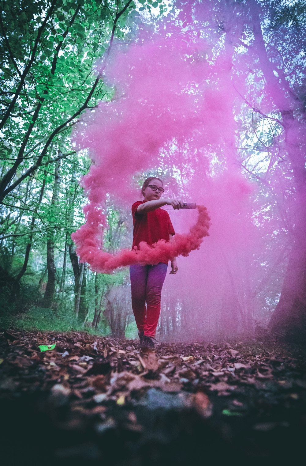 woman in pink long sleeve shirt standing on brown dried leaves covered ground