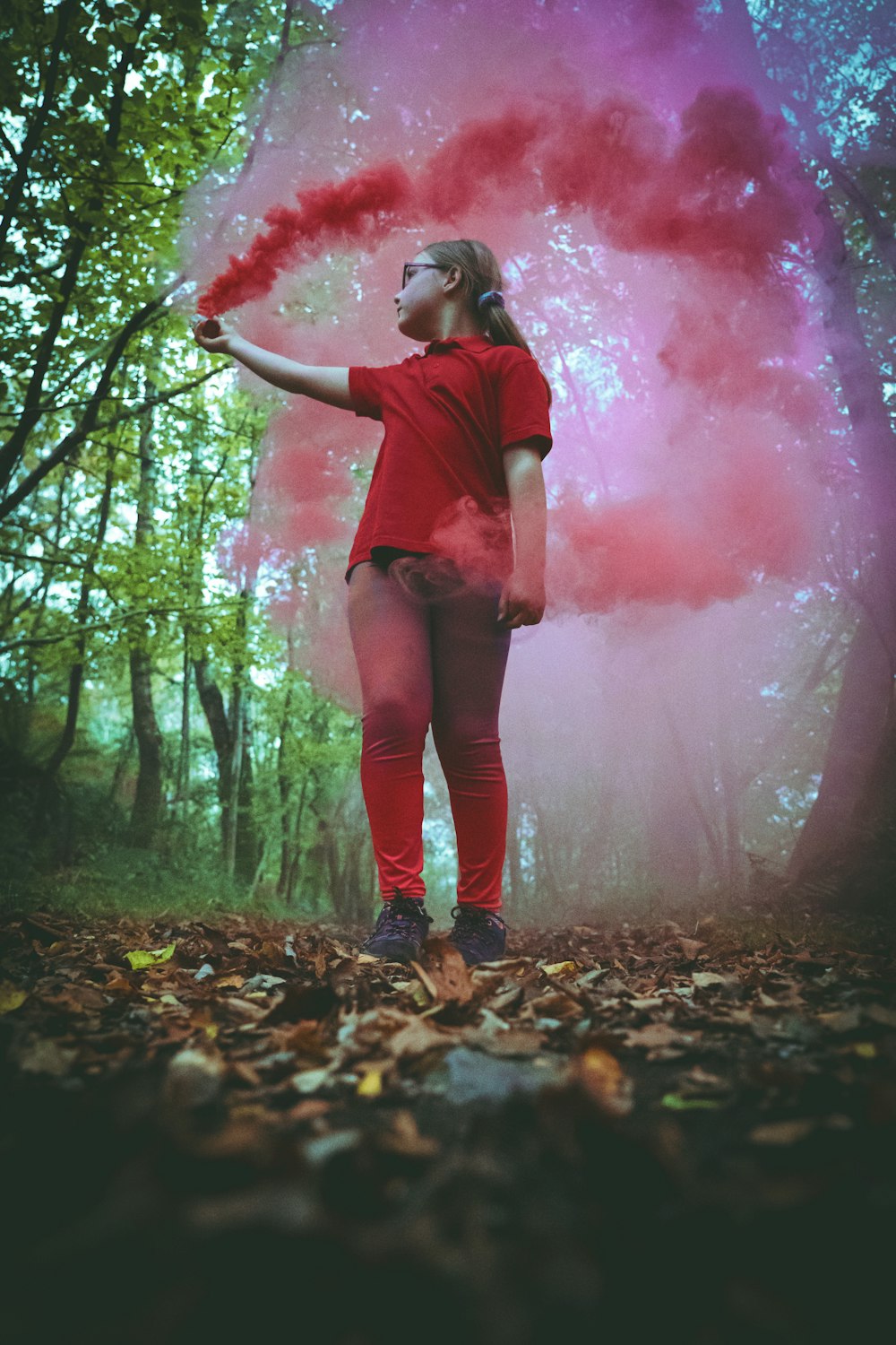 woman in red long sleeve shirt and blue denim jeans standing on brown leaves covered ground