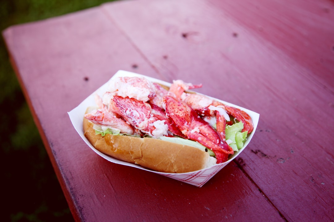 person holding bread with ham and cheese, Fresh Maine lobster roll. Affectionately called and spelled