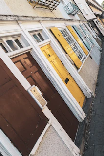 A row of colorful doors on a sunny Queens street, showcasing a variety of styles and finishes