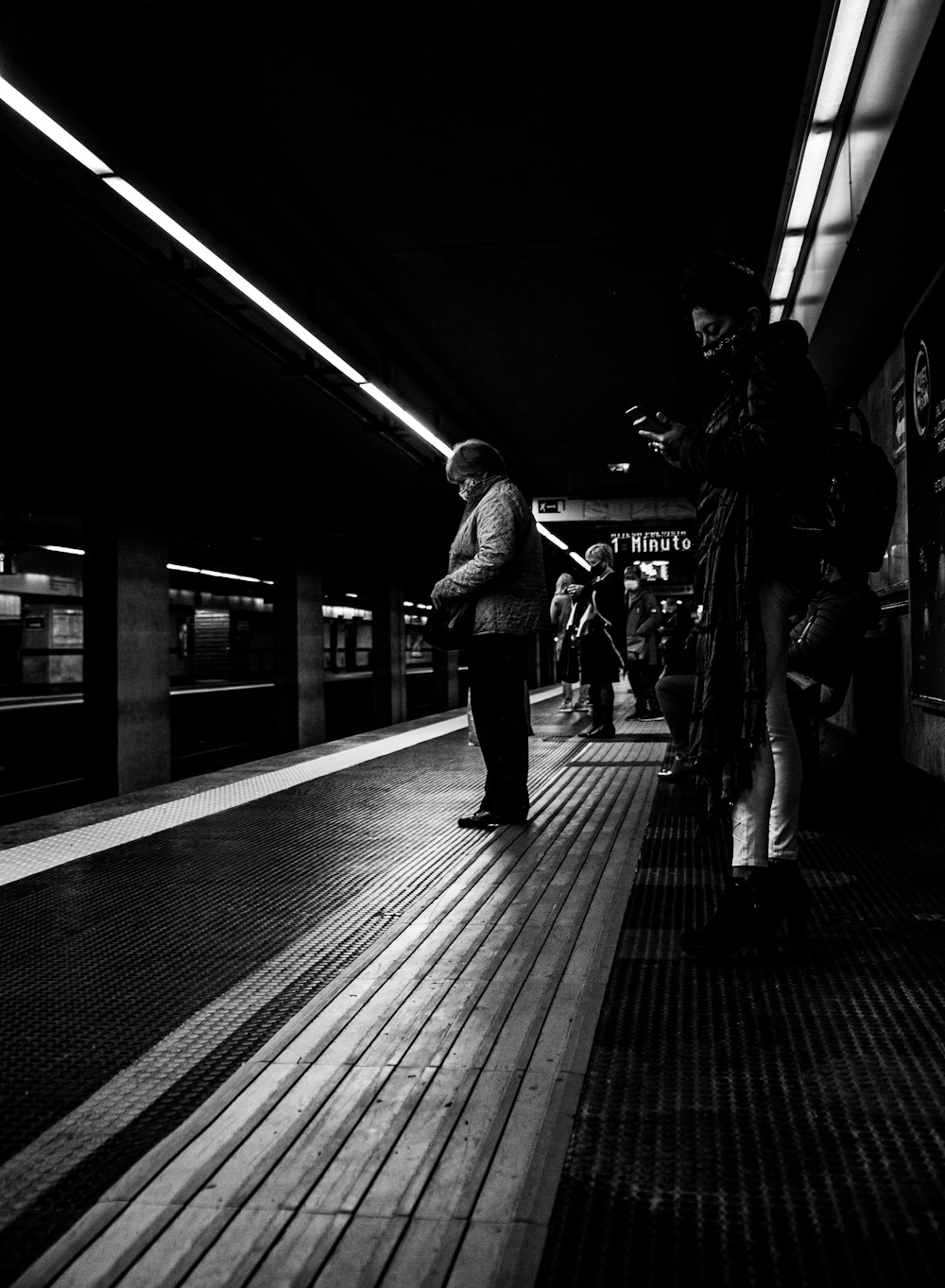 grayscale photo of man walking on train station