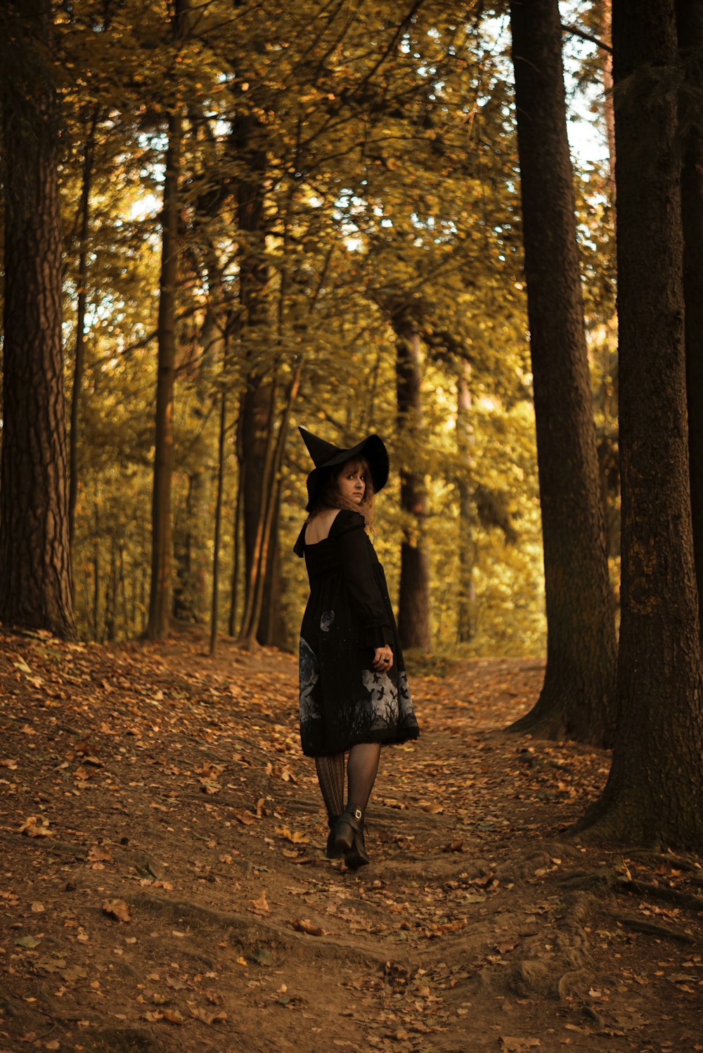 woman in black dress standing in the woods during daytime